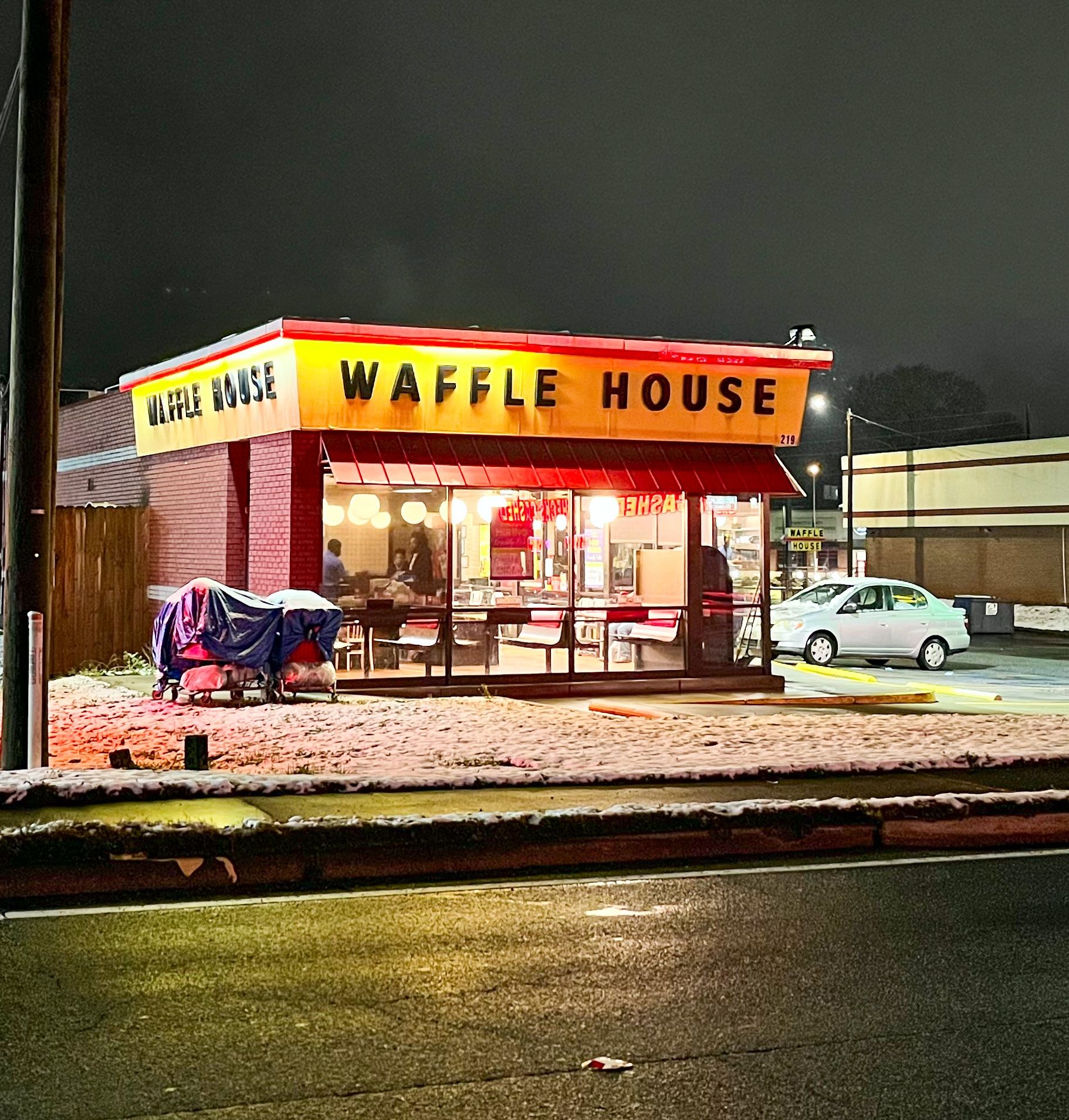 A photo of a Waffle House restaurant open at night with snow on the surrounding ground.